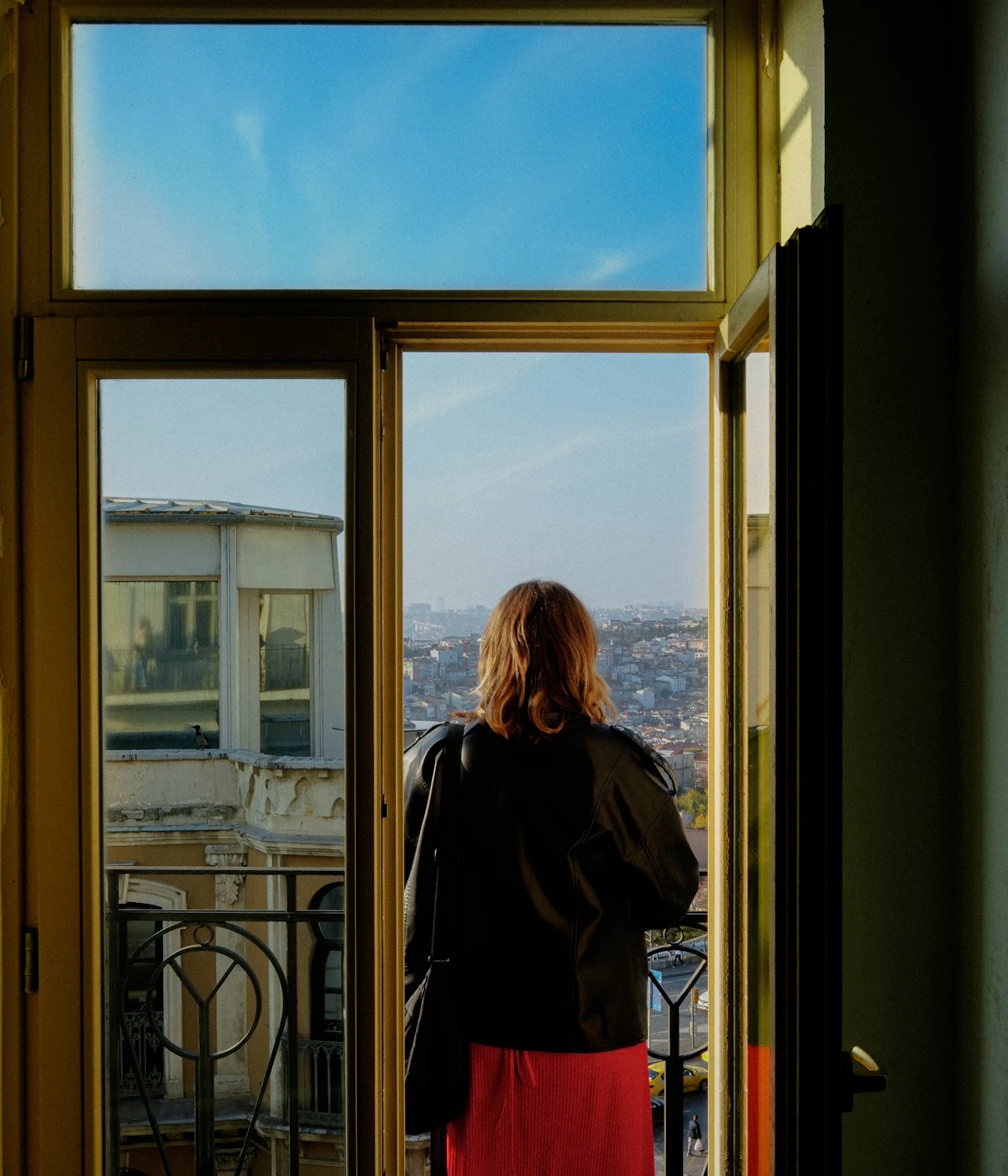 Beyoğlu'nda balkon kapısından İstanbul'a bakan bir kadın